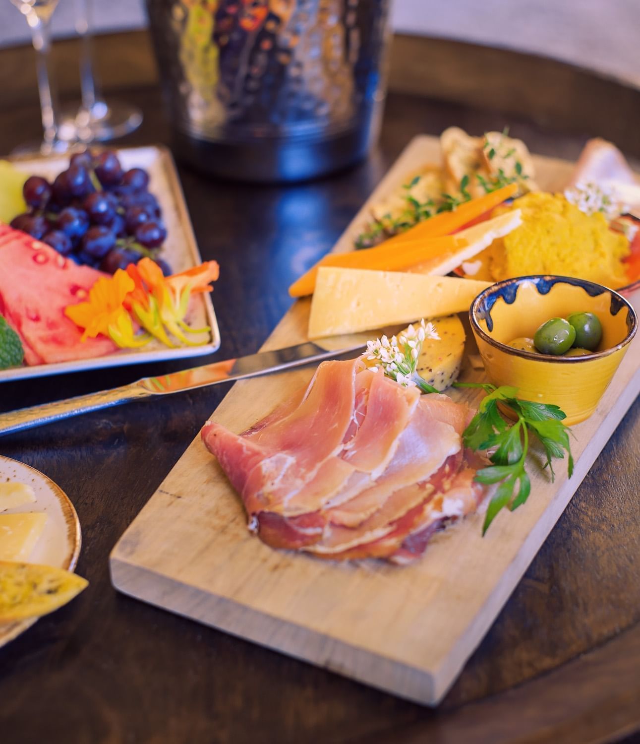 Charcuterie on a wood platter accompanied by an assortment of ch