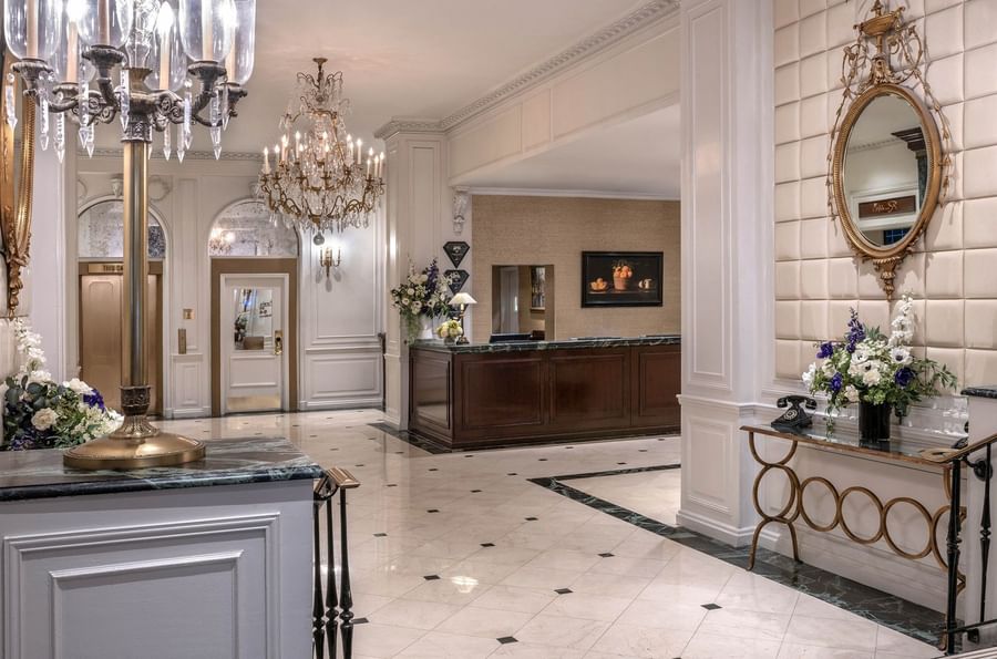 Elegant hotel lobby with chandeliers, floral arrangements, and a grand reception desk at Warwick New York.