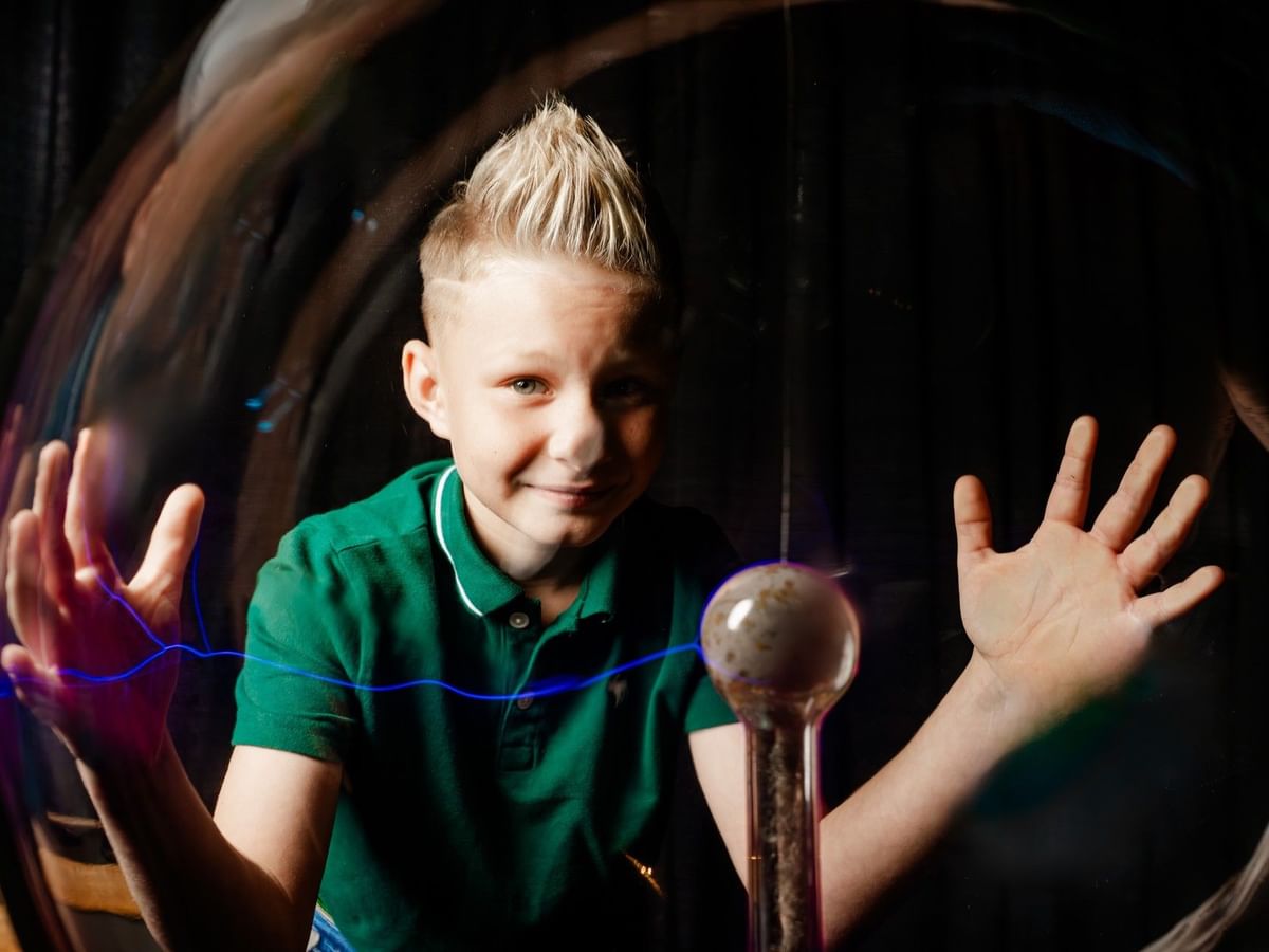Young boy by a plasma ball under dark lighting in a Mid-America Science Museum near the Arlington Resort Hotel & Spa