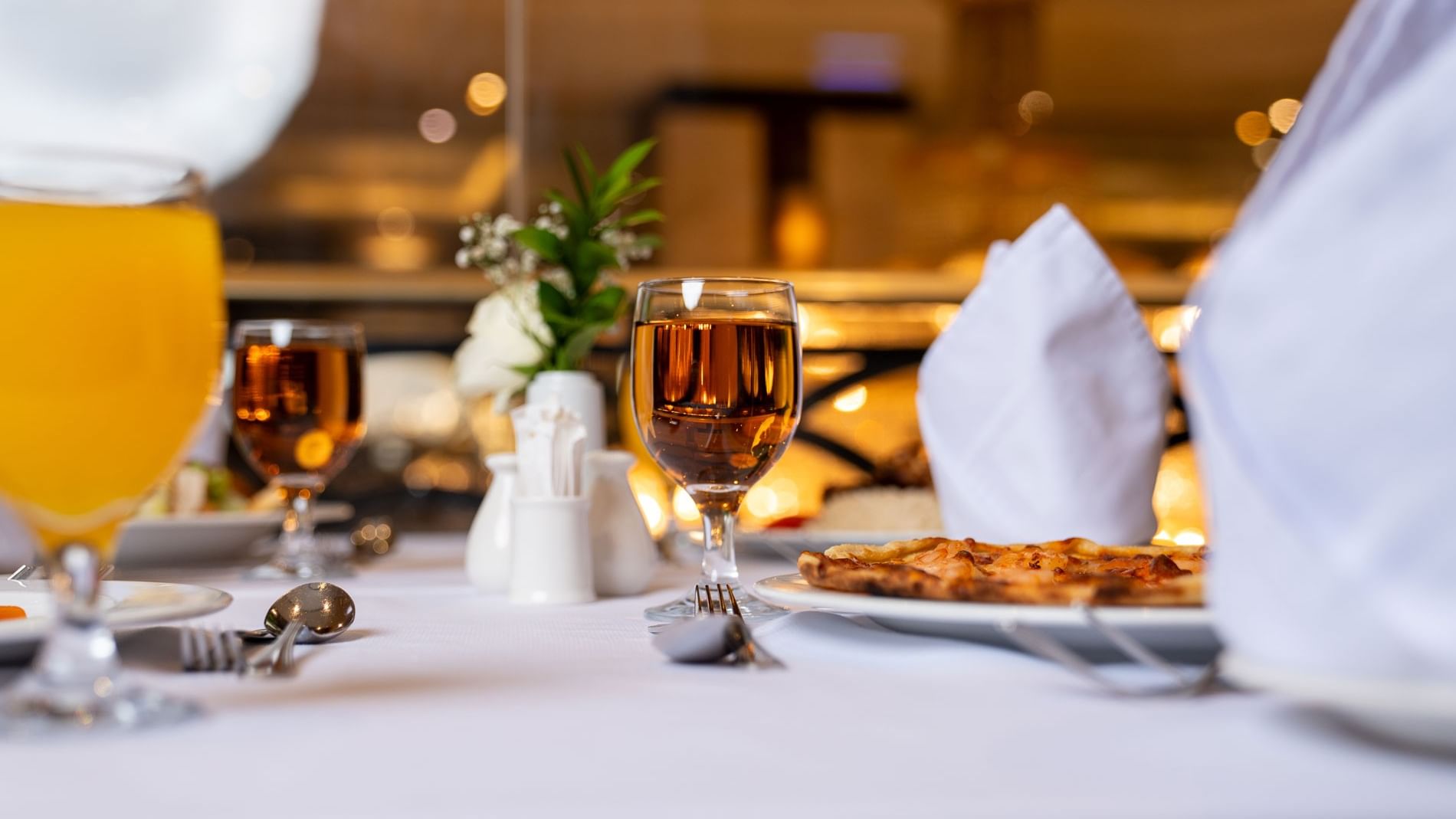 Plate with food and wine glasses on a table at Al Duhaa Restaurant, Saja by Warwick Madinah.