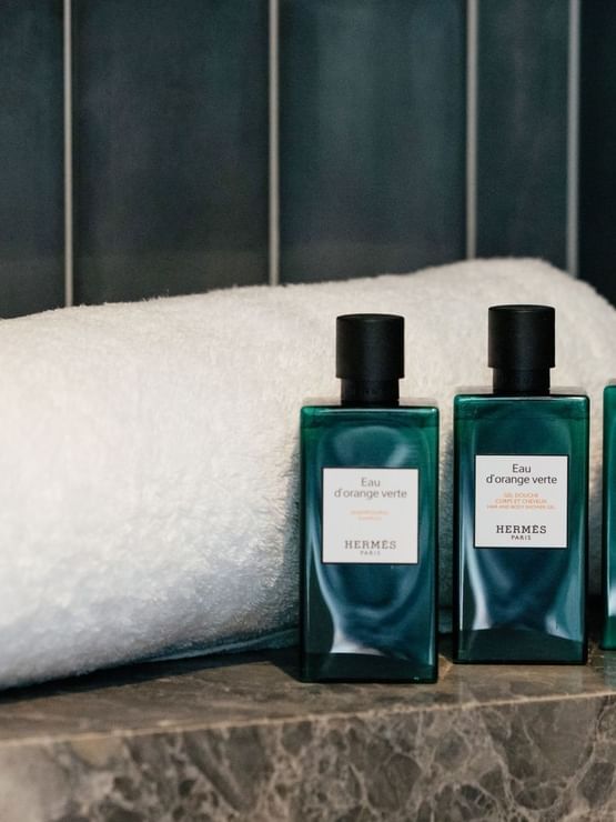 Elysium Suite with amenity bottles at Elysium Manly on a grey marble shelf near the towel, offering cozy Manly accommodation