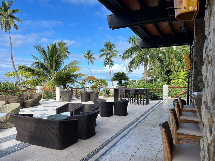 Outdoor patio with wicker furniture and ocean view at Warwick Fiji Resort and Spa.