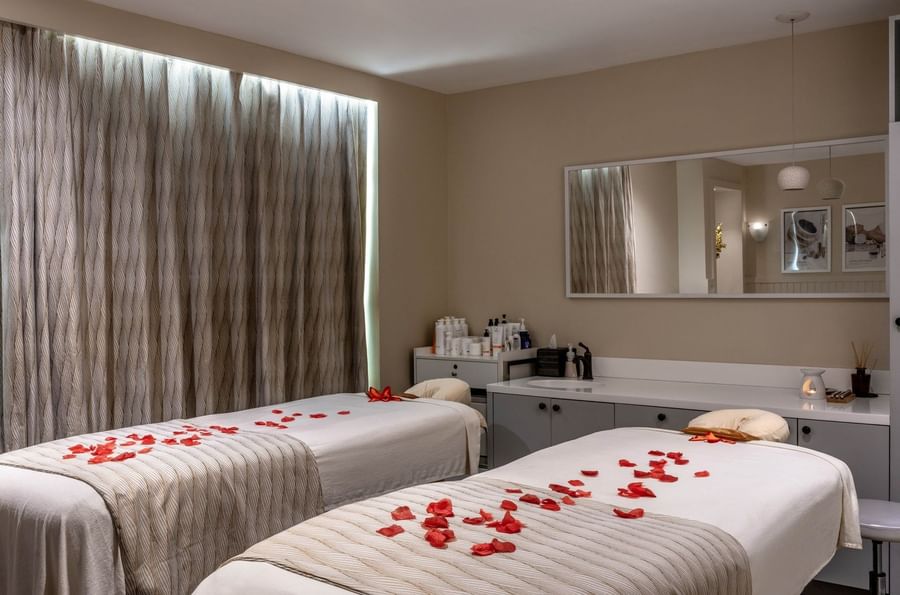 Massage tables with red flower petals by a large mirror under soft ambient light in spa at Warwick Paradise Island Bahamas