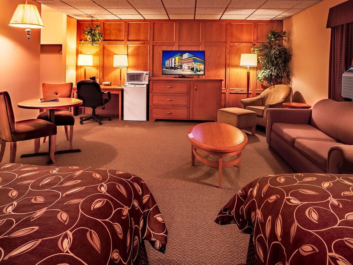 room with two beds, mini fridge, and television on dresser