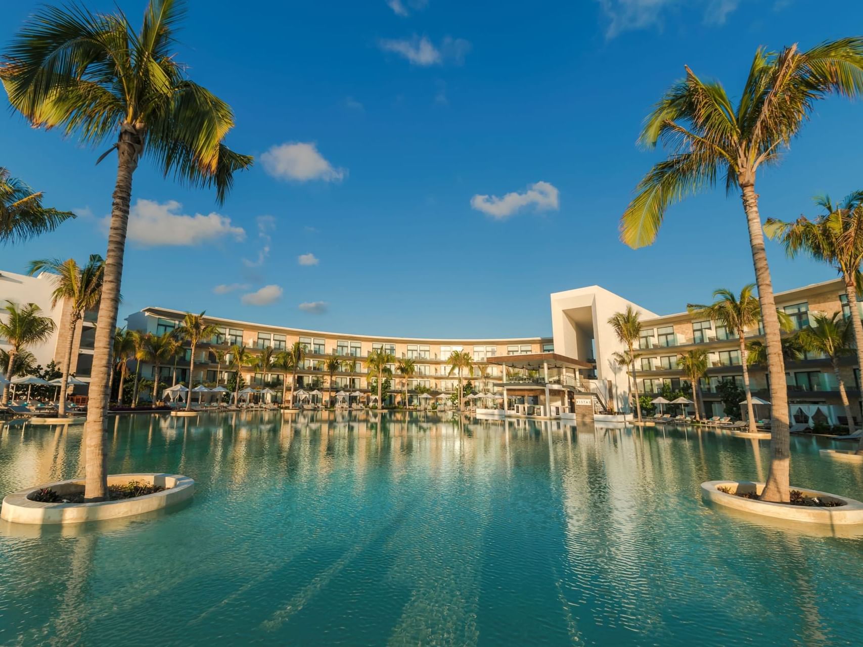Low-angle view of the pool, palm trees & hotel Haven Riviera Cancun