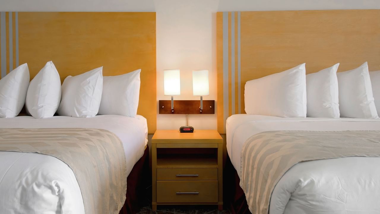 Hotel room with two queen beds neatly arranged.