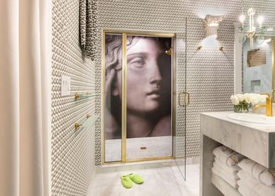 Modern bathroom with patterned wallpaper, glass shower and marble sink in Terrazza of the Titans at The Roxbury