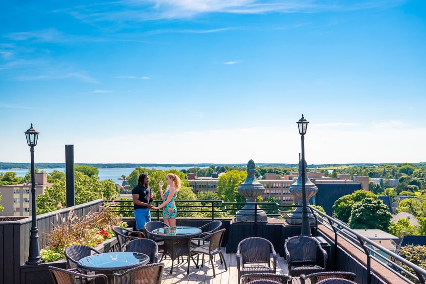 Woven chairs by patio tables under a clear blue sky at Rodd Charlottetown Hotel, one of the best hotel in PEI