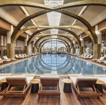 Sun loungers arranged on a wooden deck by the indoor heated pool area at Cullinan Belek