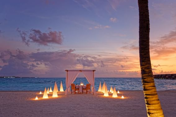 A beach setting for a romantic dinner at sunset, with a table near Grand Park Kodhipparu, Maldives