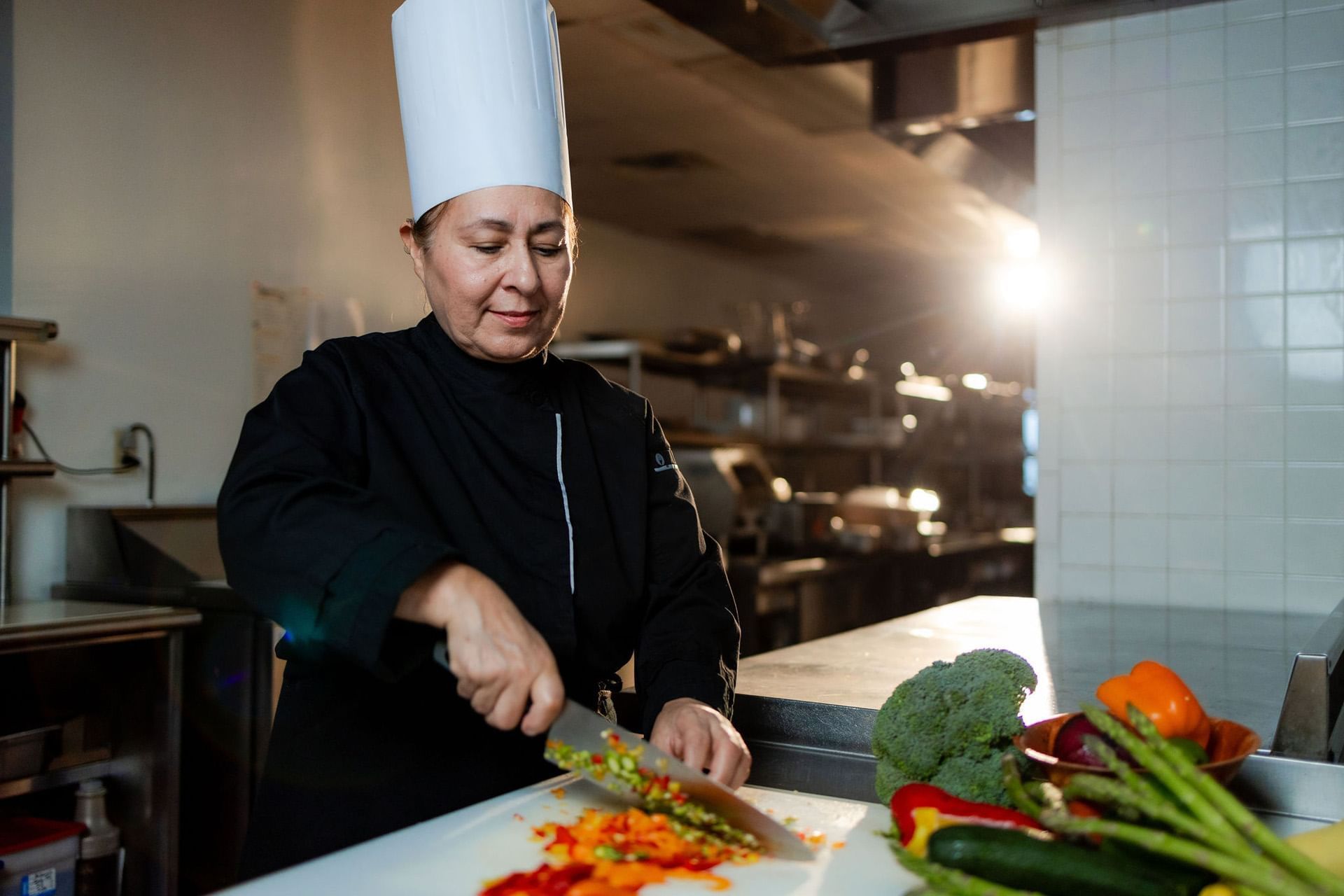 A chef in a kitchen preparing vegetables.