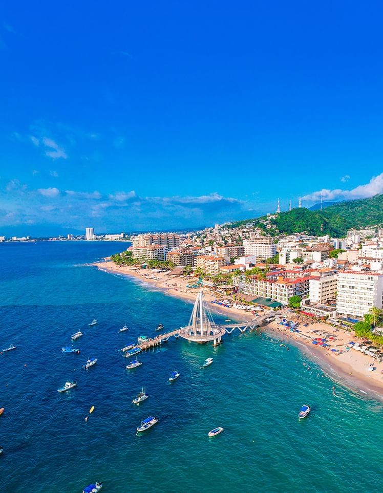Aerial view of the sail-shaped pier, surrounded by blue ocean water and boats near Playa Los Arcos Beach Resort & Spa