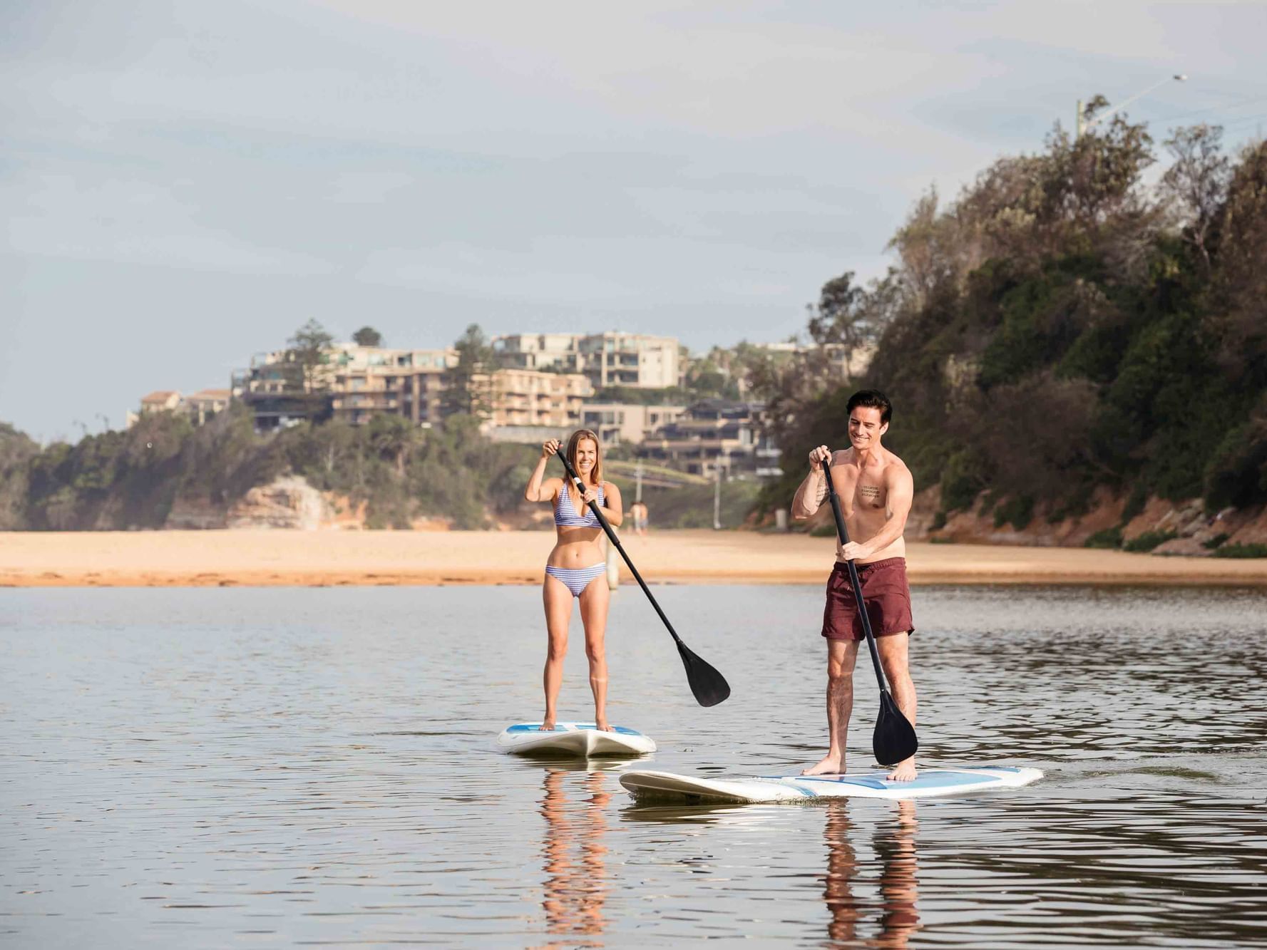 A couple paddle boarding on calm water near Pullman Magenta Shores