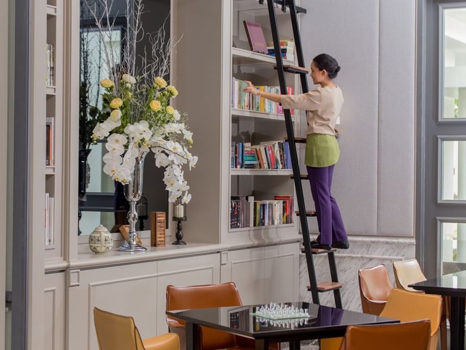 Worker arranging books in Library at U Hotels and Resorts