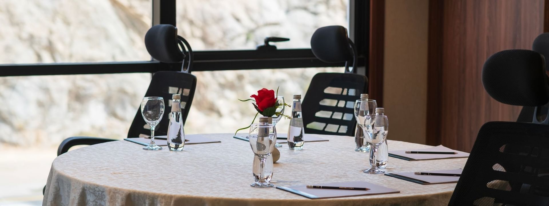 Banquet table with a single rose centerpiece and comfortable chairs in Amarige Hall at Warwick Hotels and Resorts