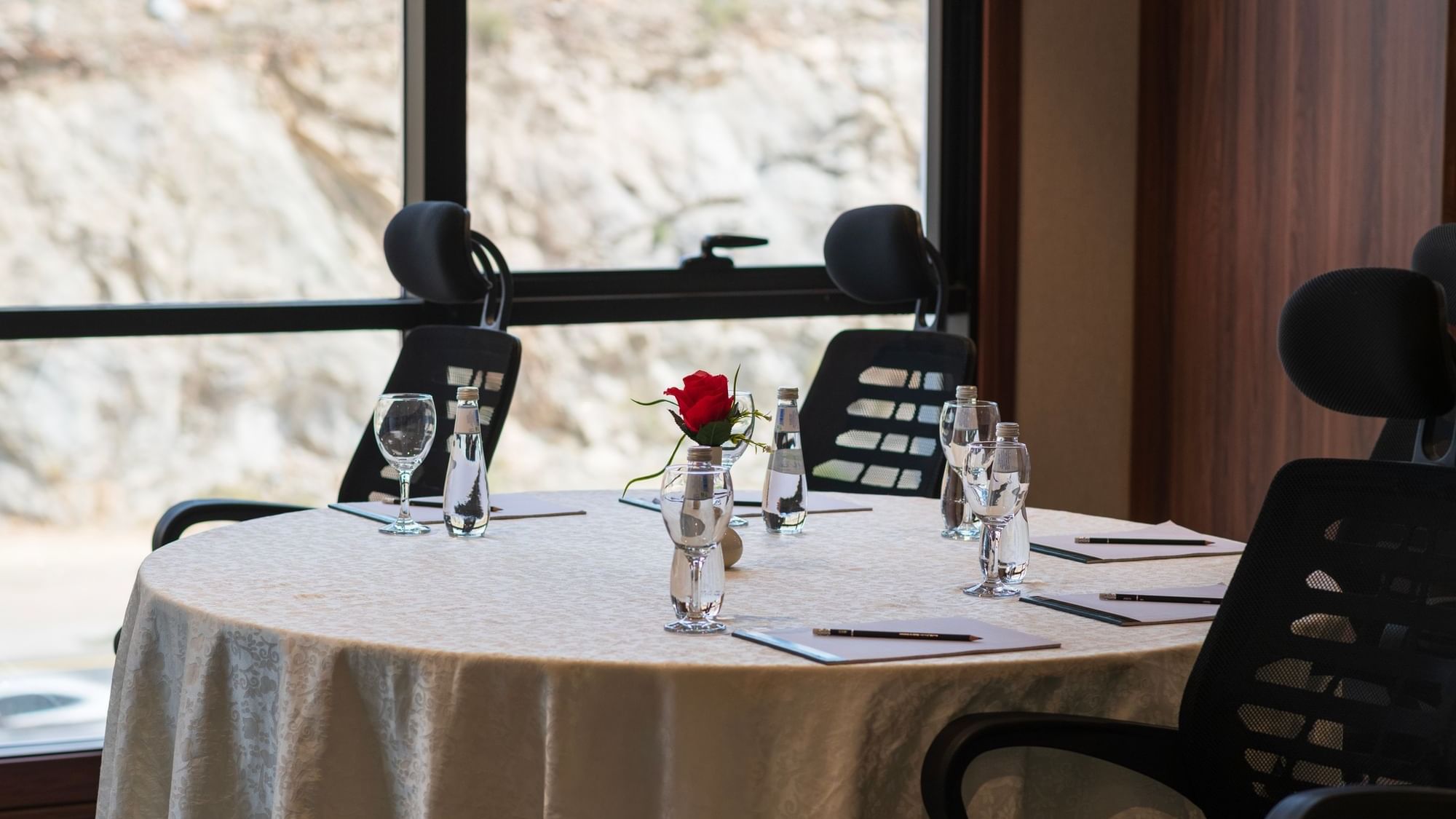 Small meeting table with a single rose centerpiece and comfortable chairs near a scenic view at Warwick Hotels and Resorts