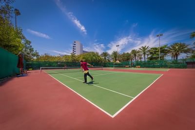 A man playing tennis at tennis court in Ajman Hotel