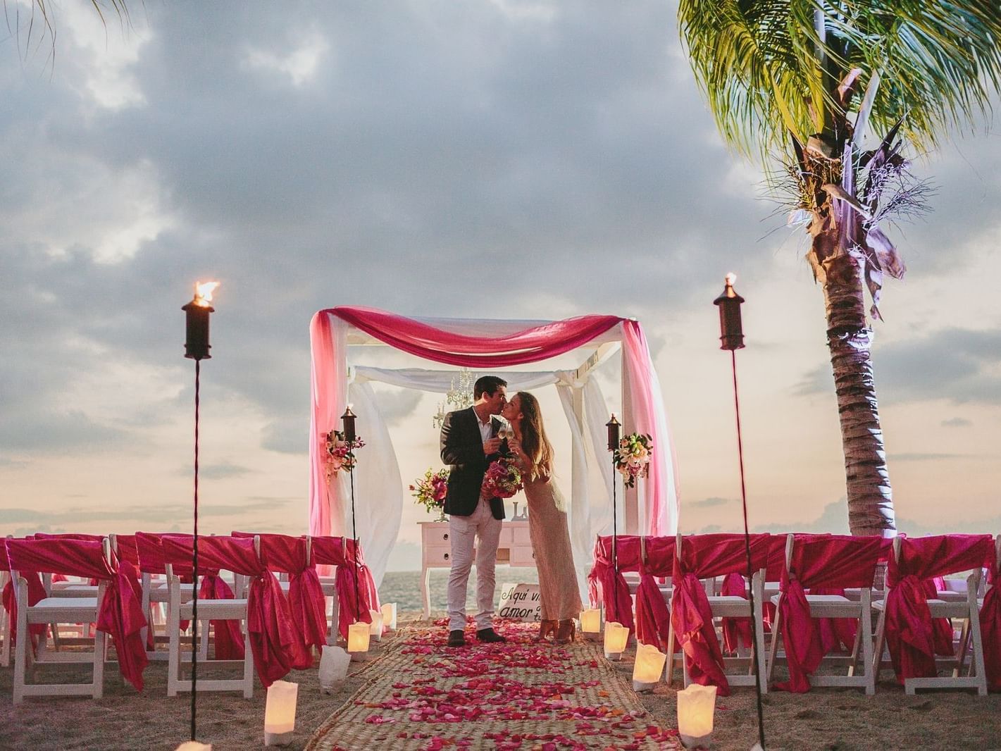 Couple kissing by the aisle at an outdoor wedding, La Colección