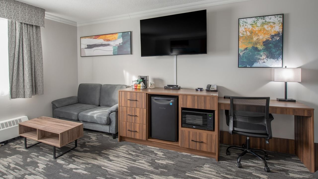 Hotel room interior with a couch, desk, TV, and microwave.