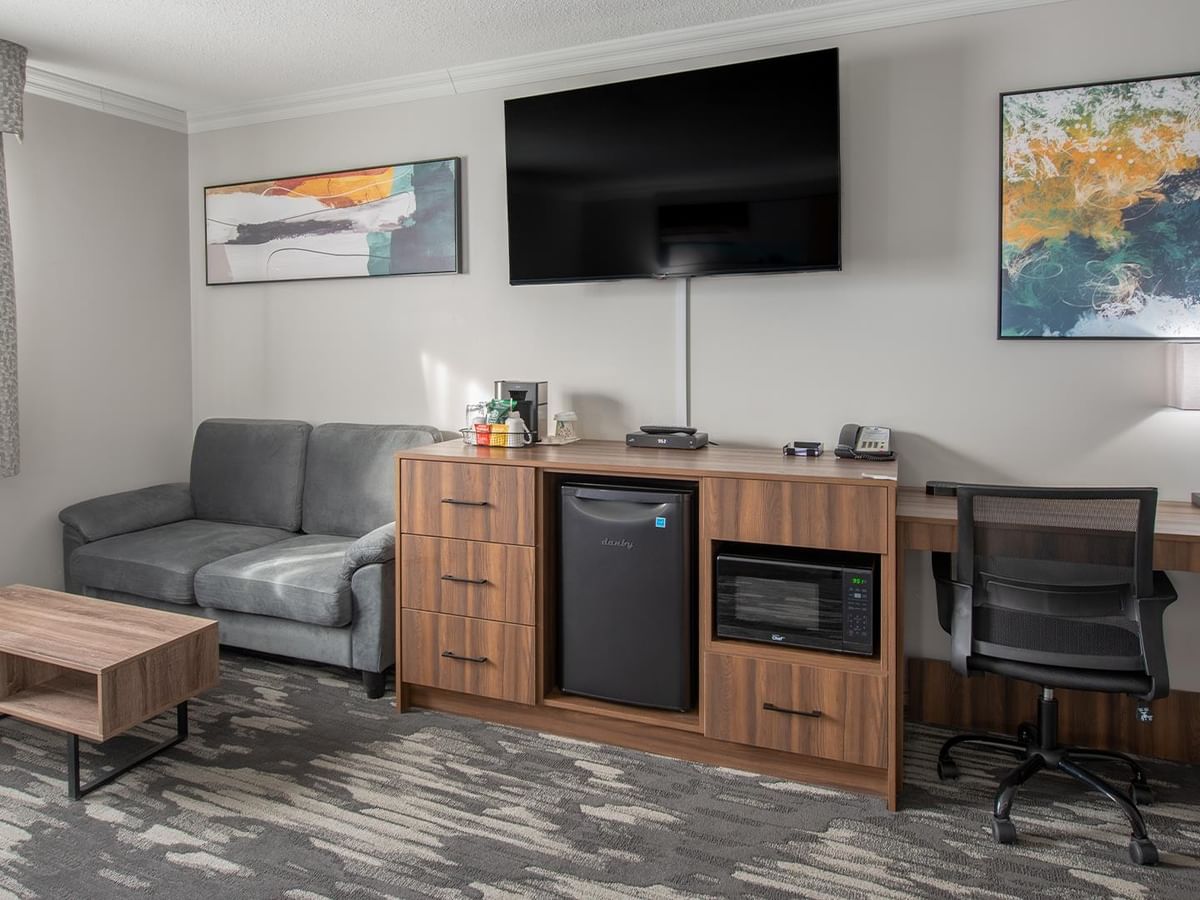 Comfortable room with couch, desk, chair, and TV.