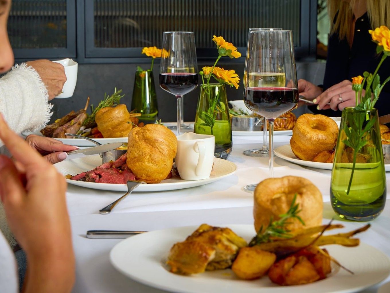 Uma família a saborear um jantar com carne assada, Yorkshire puddings e vinho tinto no Whitcomb's.