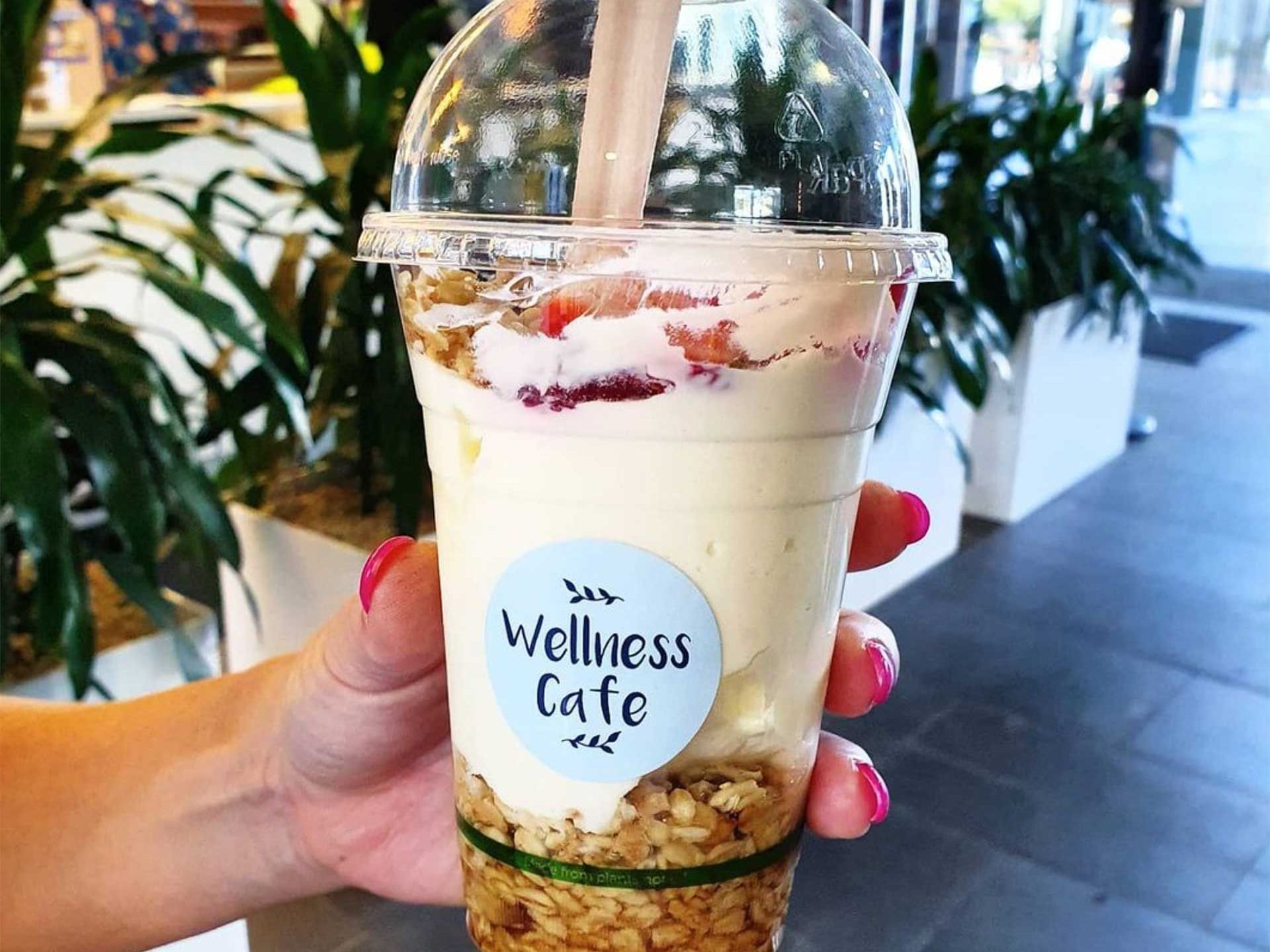 A person holding a cup of yoghurt topped drink from wellness cafe at Encore by Mingara