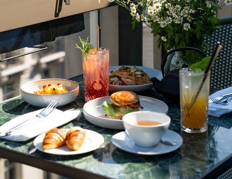 Rooftop table with drinks, pastries, and flowers at Restaurant, Bar & Terrace Le W, the best bars near Champs-Élysées