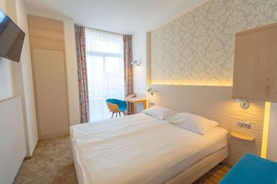 Bedroom with double bed, TV and work desk in Metropol Hotel
