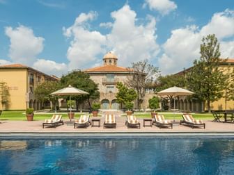 Luxury pool area featuring striped lounge chairs and elegant colonial architecture at Quinta Real Aguascalientes