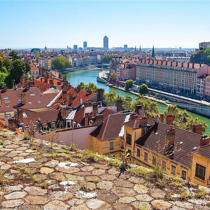 Panoramic view of Lyon, featuring riverbanks, colorful rooftops, and modern buildings near Warwick Hotels and Resorts