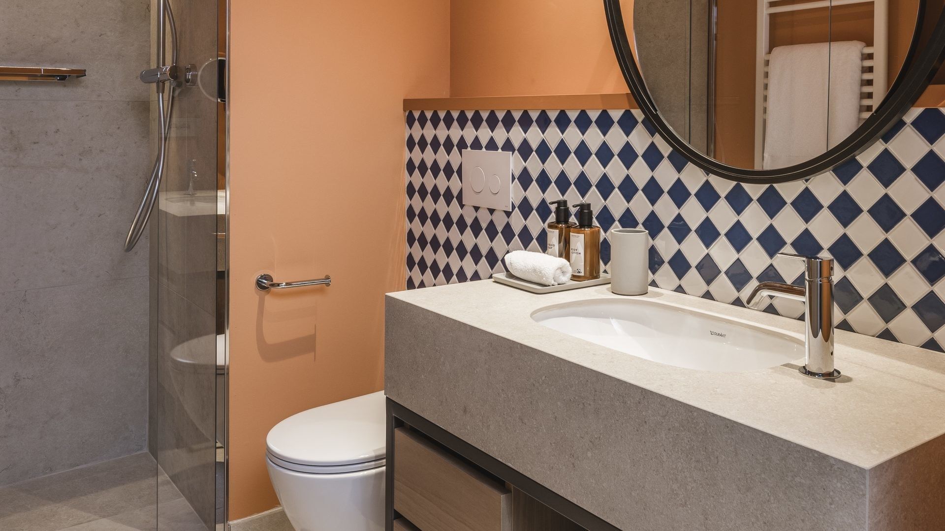 Bagno moderno con doccia, WC, lavabo, specchio, asciugamani e decorazioni blu e bianche.