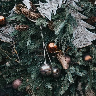 Tannenzweige mit Kugeln, Zapfen und silbernen Baumdekorationen, die auf einem Weihnachtsbaum hängen.