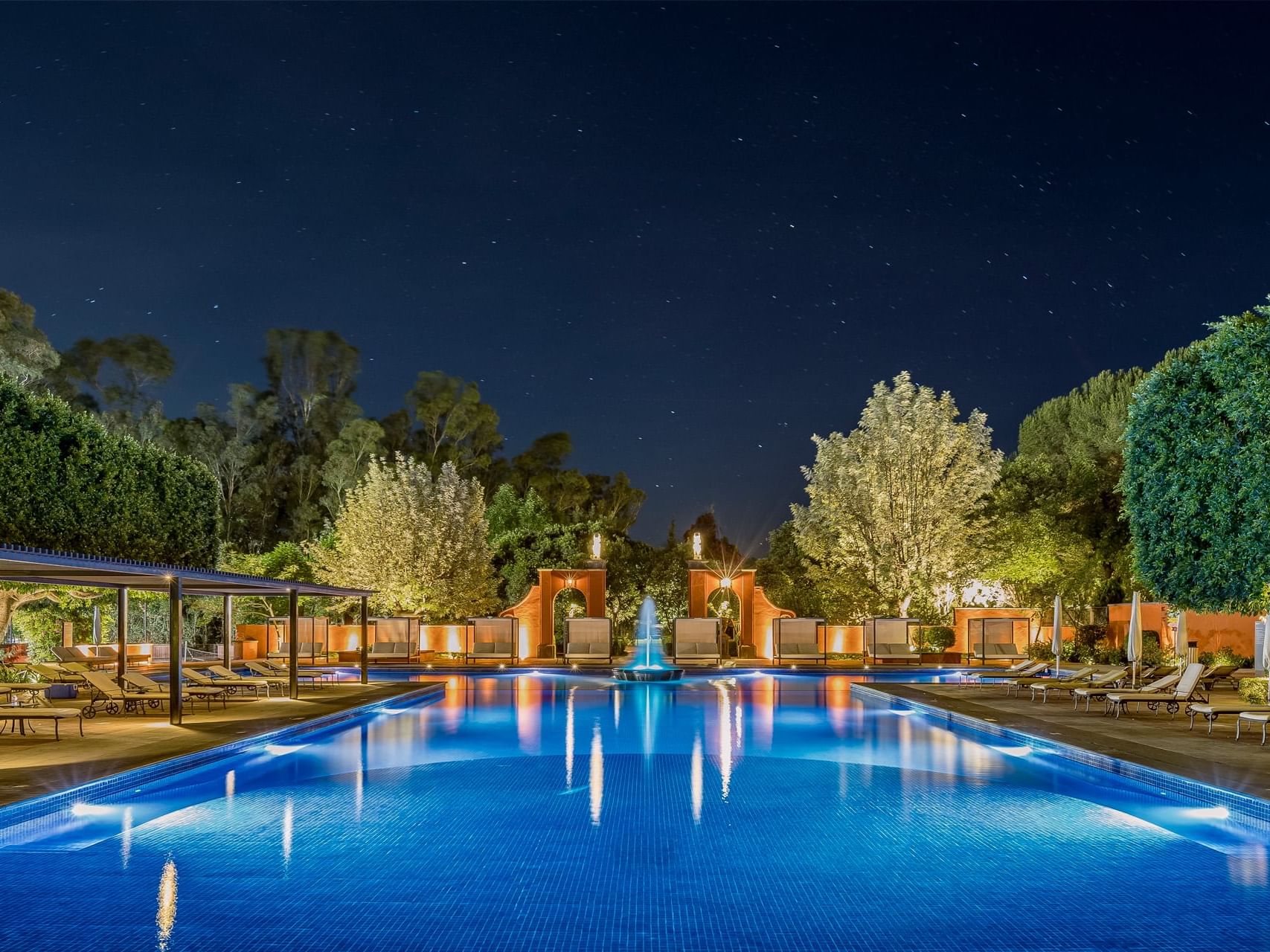 Outdoor pool with a fountain & sunbeds at La Colección Resorts