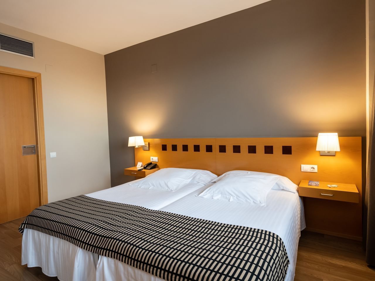 Large bed, comfy pillows & bedside lamps in Adapted Room at Hotel Vila Centric