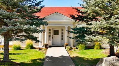 Presidential cottage with a red roof at The Stanley Hotel, with a stone walkway and pine trees on either side
