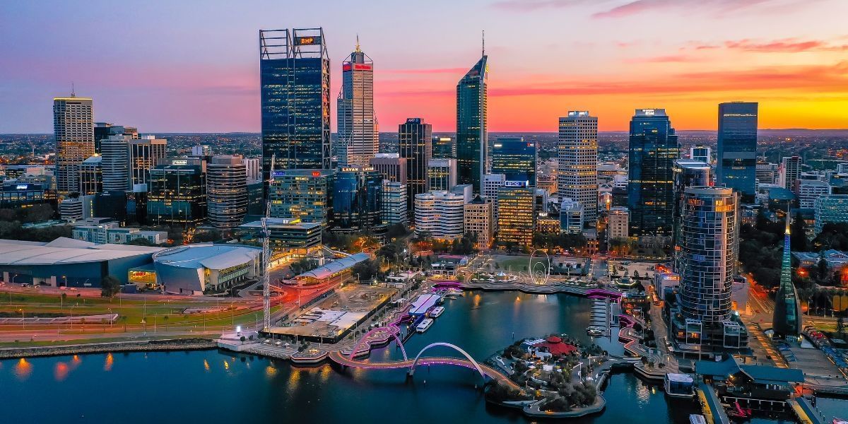 An aerial view of the Perth city skyline and waterfront at sunset with the Novotel Perth Langley in the distance