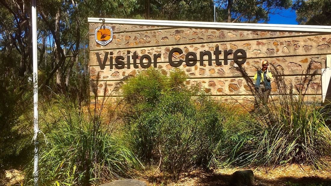 Entrance sign for the Blue Mountains Heritage Centre with visitor and flag visible.