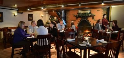 Tables of happy guests eating beside a fireplace