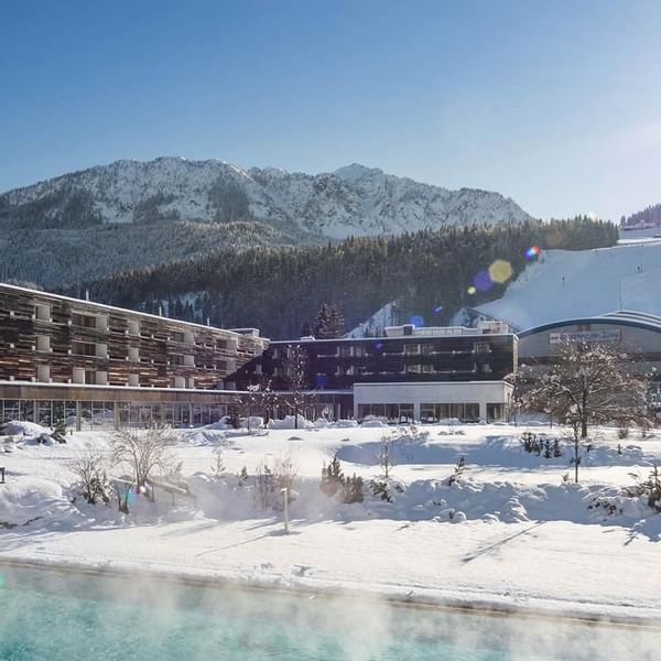 Distant view of the hotel and heated pool in winter at Falkensteiner Hotel Kronplatz