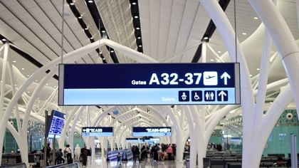 مبنى مطار حديث يتميز بأقواس معمارية بيضاء ولافتات إرشادية للبوابات من A32 إلى A37 في مطار الملك عبد العزيز الدولي