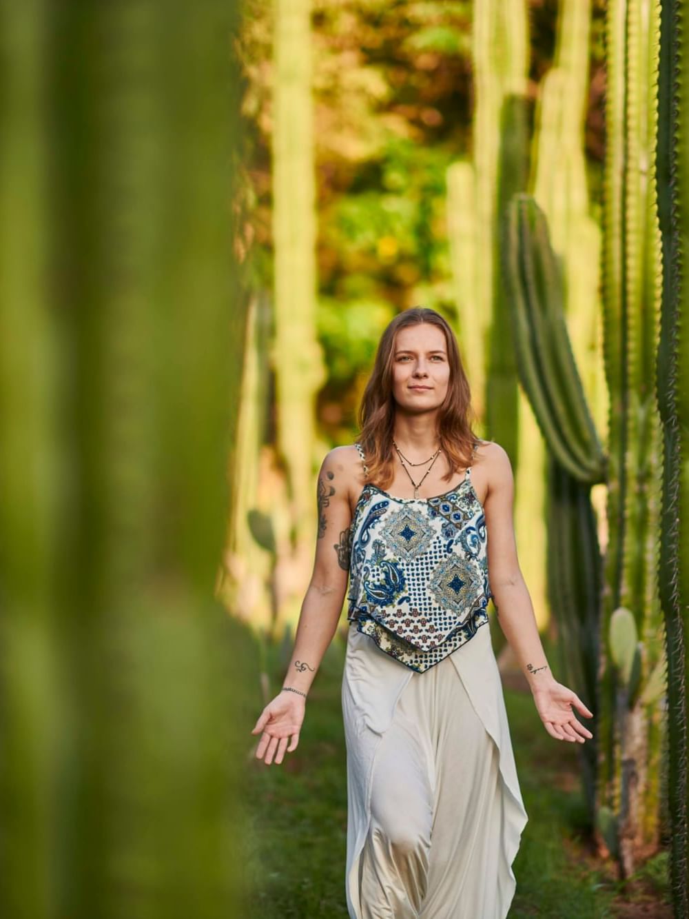 Woman walking peacefully through tall green cacti garden for Awaken Within, Signature Retreat at Cala Luna.