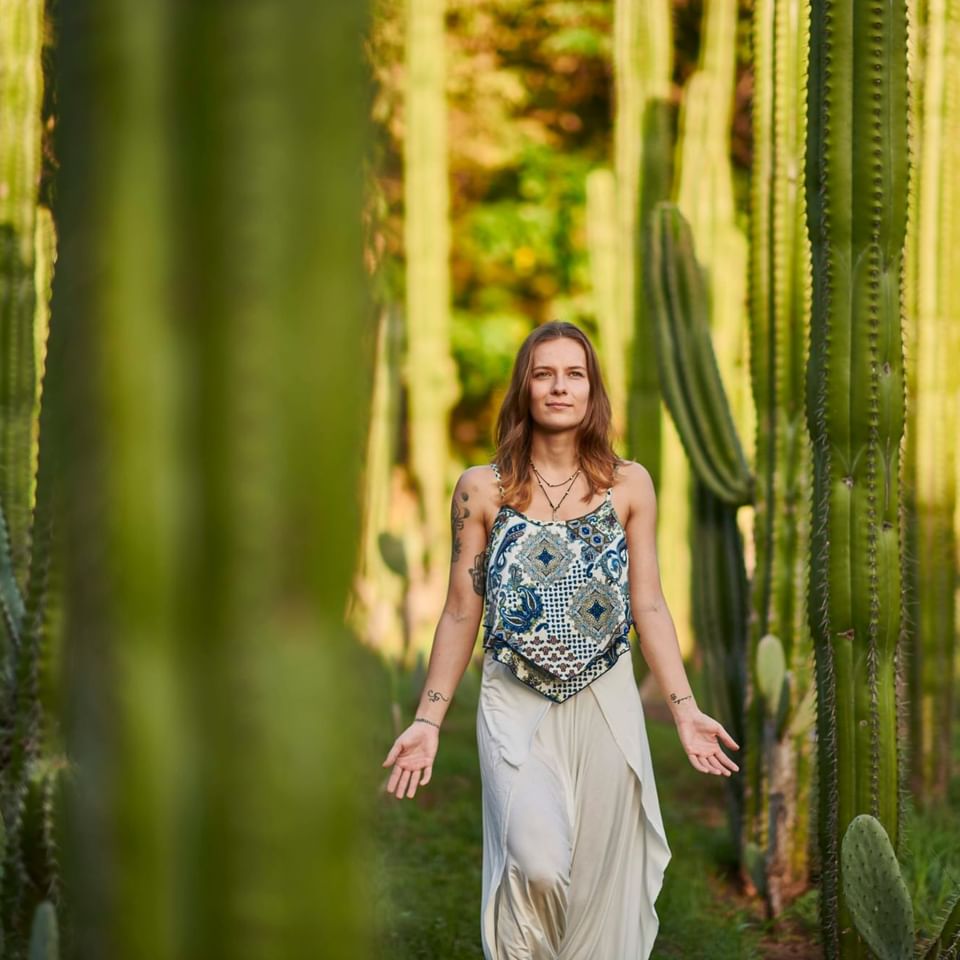 Mujer caminando serenamente entre cactus altos en un jardín natural durante el Despertar Interior, Retiro Signature.