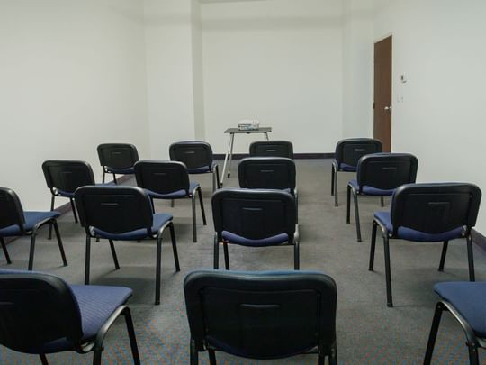 Classroom-style Alcatraces meeting room with blue chairs and a projector at Camino Real Pachuca