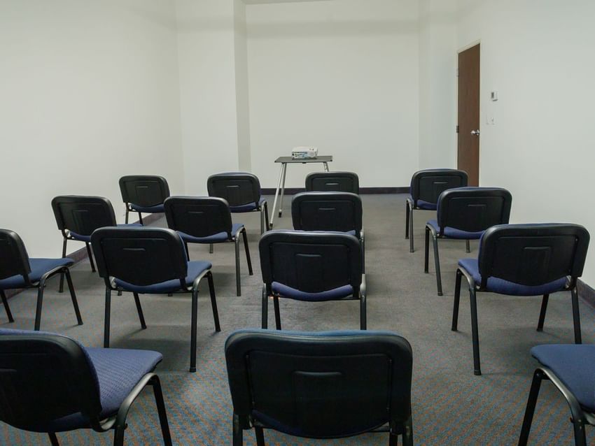 Classroom-style Alcatraces meeting room with blue chairs and a projector at Camino Real Pachuca
