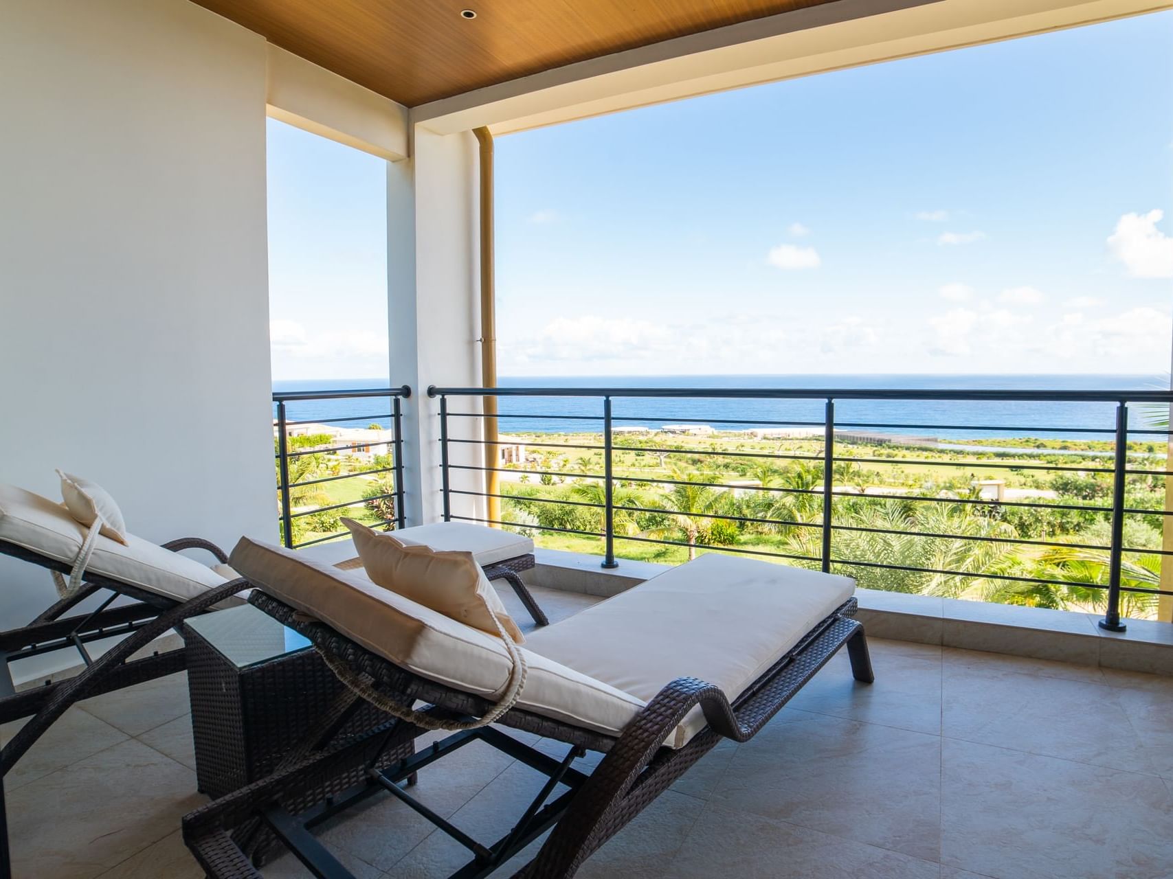 Stylish balcony with two loungers overlooking a lush greenery and the ocean in Deluxe Ocean View Room at Golden Rock Resort