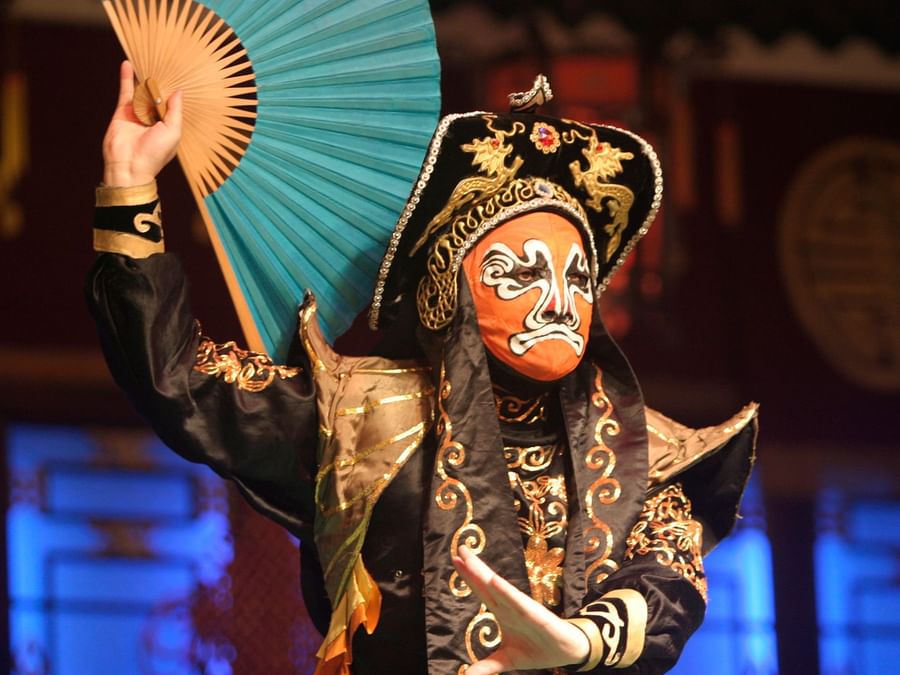 Person in traditional attire holding a blue fan at Dubai Opera near DAMAC Hotels & Resorts, the best family hotels in Dubai