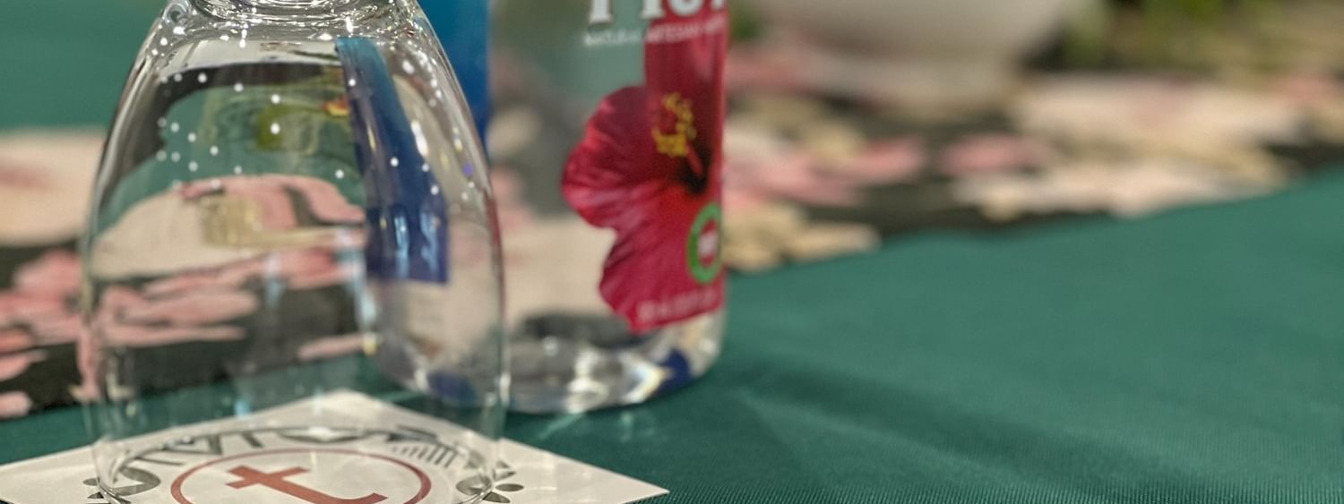 Bottle of Fiji water, wine glass, pen, and paper on a table at Tokatoka Resort Nadi