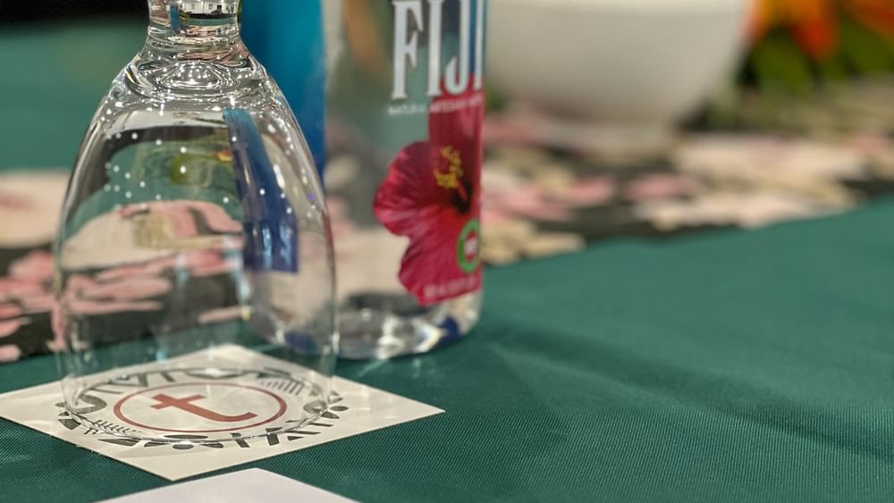 Bottle of Fiji water, wine glass, pen, and paper on a table at Tokatoka Resort Nadi.