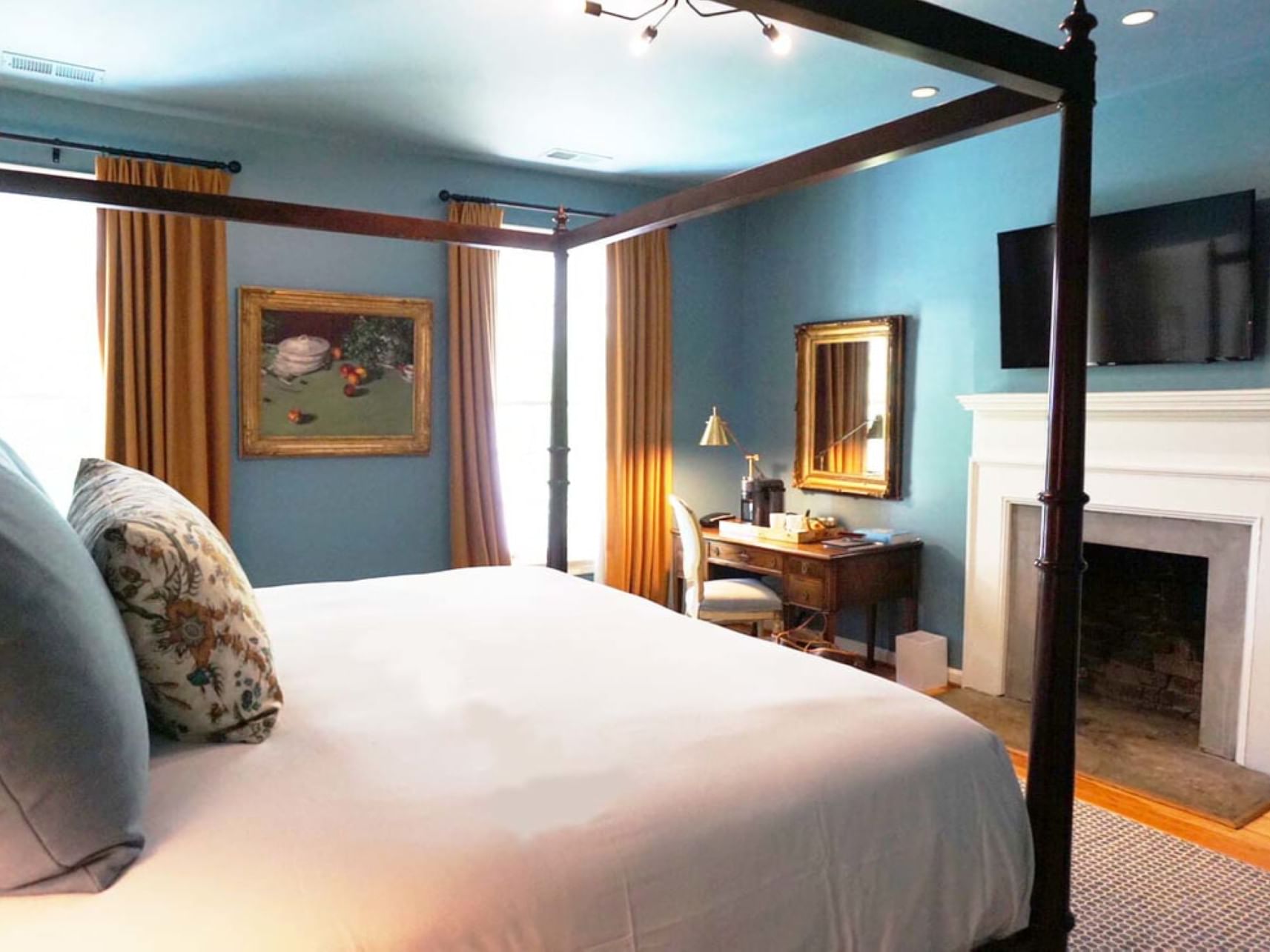 Four-poster bed in Thomas Jefferson room with fireplace and artwork at The Clifton in Charlottesville.