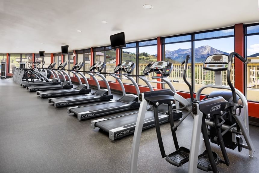 Treadmills and elliptical machines in a gym with large windows and mountain views at Elevation Resort Spa